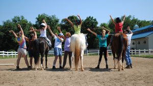 TRAV kids on horses with their hands in the air